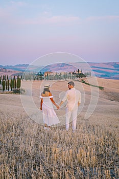 Tuscany, Crete Senesi rural sunset landscape. Countryside farm, cypresses trees, green field, sun light and cloud. Italy