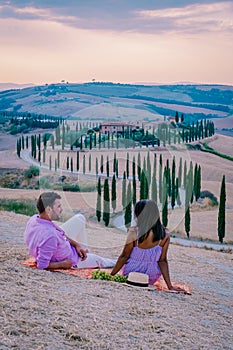 Tuscany, Crete Senesi rural sunset landscape. Countryside farm, cypresses trees, green field, sun light and cloud. Italy