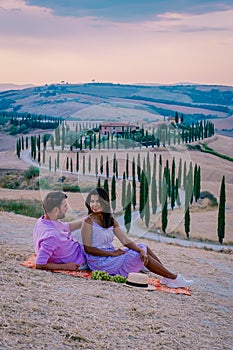 Tuscany, Crete Senesi rural sunset landscape. Countryside farm, cypresses trees, green field, sun light and cloud. Italy