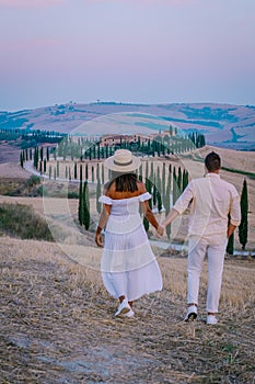 Tuscany, Crete Senesi rural sunset landscape. Countryside farm, cypresses trees, green field, sun light and cloud. Italy