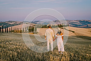 Tuscany, Crete Senesi rural sunset landscape. Countryside farm, cypresses trees, green field, sun light and cloud. Italy