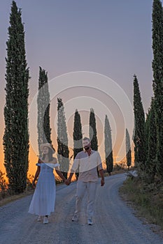 Tuscany, Crete Senesi rural sunset landscape. Countryside farm, cypresses trees, green field, sun light and cloud. Italy