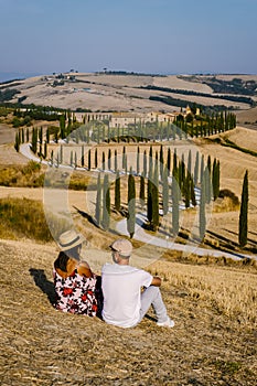 Tuscany, Crete Senesi rural sunset landscape. Countryside farm, cypresses trees, green field, sun light and cloud. Italy