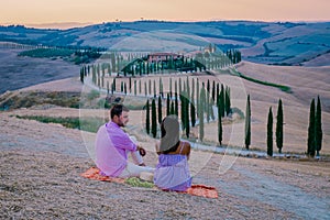 Tuscany, Crete Senesi rural sunset landscape. Countryside farm, cypresses trees, green field, sun light and cloud. Italy