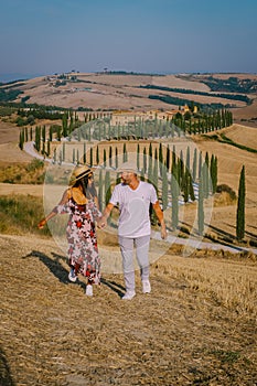 Tuscany, Crete Senesi rural sunset landscape. Countryside farm, cypresses trees, green field, sun light and cloud. Italy