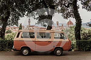 Tuscany, Italy. orange minibus surrounded by green trees with a beautiful panoramic view of the city of Florence