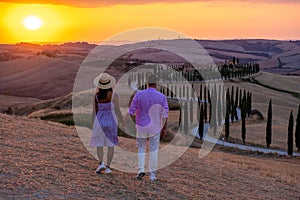 Tuscany landscape with grain fields, cypress trees and houses on the hills at sunset. Summer rural landscape with curved