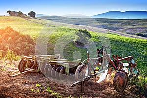 Tuscany landscape at sunrise. Retro agriculture machines. Italy