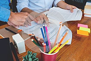 Tutor and college students teaching school work and explaining problem solution studying and reading together in a table at class