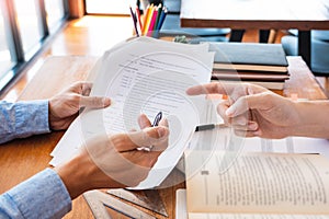 Tutor and college students teaching school work and explaining problem solution studying and reading together in a table at class