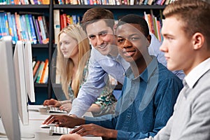 Tutor With Group Of Teenage Students Using Computers