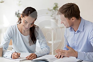 Tutor helping female student making notes with research work photo