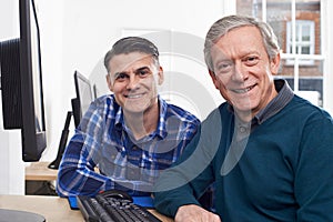Tutor Helping Mature Man In Computer Class