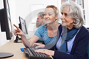 Tutor Helping Senior Woman In Computer Class