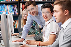 Tutor Helping Teenage Students Wotking At Computers