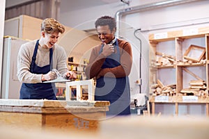 Tutor With Male Carpentry Student In Workshop Studying For Apprenticeship At College