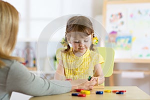 Tutor and preschooler kid playing with educational toys