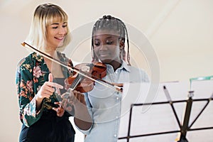 Tutor Teaching High School Student To Play Violin In Music Lesson