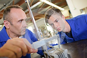 Tutor using vernier guage apprentice watching