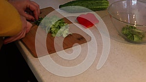 Tutorial cropped woman hands cook, chopping cucumber with sharp kitchen knife on wooden cutting board. Healthy eating