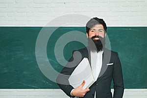 Tutoring. Back to school and happy time. Bearded professor at school lesson at desks in classroom. Teacher preparing for
