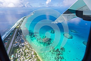 Tuvalu island azure turquoise blue lagoon under the wing of an airplane, aerial view. Polynesia, Oceania.