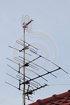 Tv antenna above roof at home , receiver communication data with blue sky