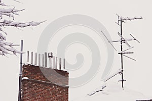 The TV antenna is covered with snow on the roof. Cold winter, , icicle formation, frost and winter weather concept.