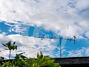 TV antenna with silhouette two birds kissing on outdoor in blue white sky background in rural place.