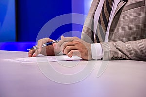 Tv host tv reporter tv journalist hands writing down on paper with pen in tv studio