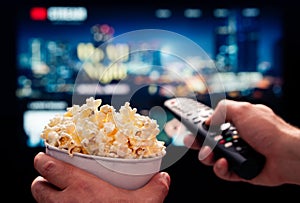 Tv movie night with family. Stream VOD platform. Popcorn and remote control. Video entertainment and snack. Play online.