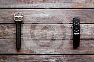 TV news concept. TV remote and microphone on dark wooden background top-down copy space