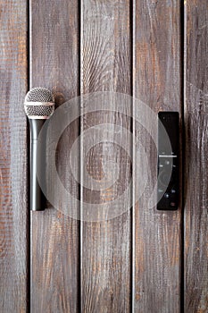 TV news concept. TV remote and microphone on dark wooden background top-down copy space