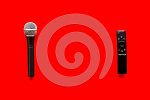 TV news concept. TV remote and microphone on red background top-down copy space