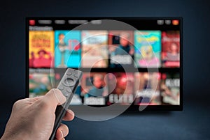 Tv online. Television streaming video. Male hand holding TV remote control. Multimedia streaming concept. VoD content provider.