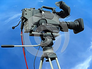 TV Professional studio digital video camera on tripod over blue sky