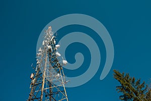 Tv or radio antenna, communications tower on the top of the hill on a small clearing and blue skies. Antenna above Lasko at Malic