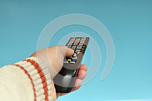 Tv remote control in the hand of a man on a blue background