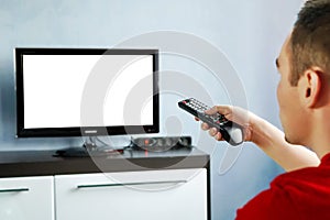 TV remote control in male hand in front of widescreen TV set with blank screen on blue wall background. Young guy switches channel