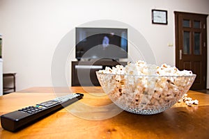 Tv remote control and popcorn on a wooden brown coffee table