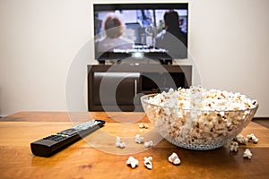 Tv remote control and popcorn on a wooden brown coffee table