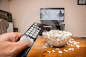 Tv remote control and popcorn on a wooden brown coffee table