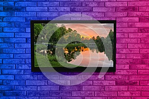 TV screen with beautiful landscape on brick wall in neon lights