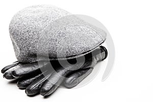 Tweed grey cap black leather gloves white background