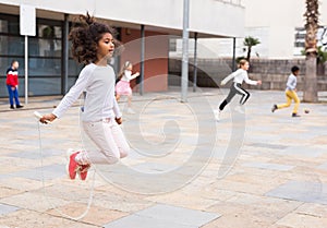 Tween African American girl skipping rope in schoolyard