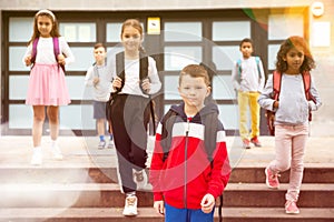 Tween boy with backpack walking to school campus after lessons