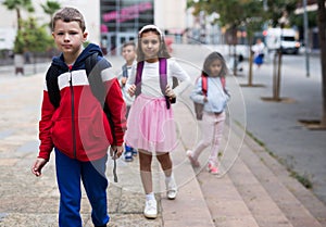Tween boy with backpack walking to school campus after lessons