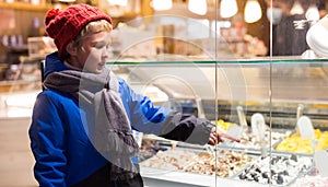 Tween boy pointing to ice cream display case outdoors