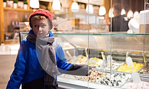 Tween boy pointing to ice cream display case outdoors