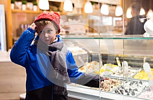 Tween boy pointing to ice cream display case outdoors